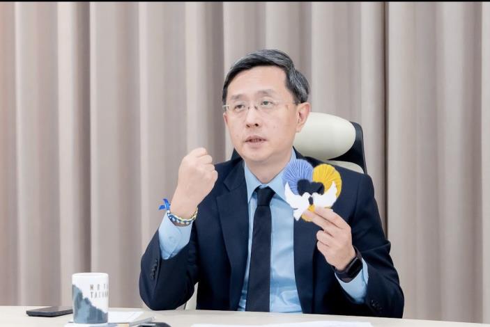 圖說二：外交部政務次長李淳展示由戰區兒童在防空洞避難時製作的藍黃相間手環及鑲有和平白鴿的心型手工藝。 