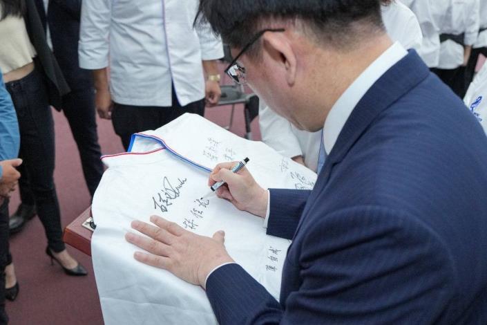 圖說四：外交部長林佳龍於代表隊廚師服上簽名，以勉勵代表隊為國爭光。