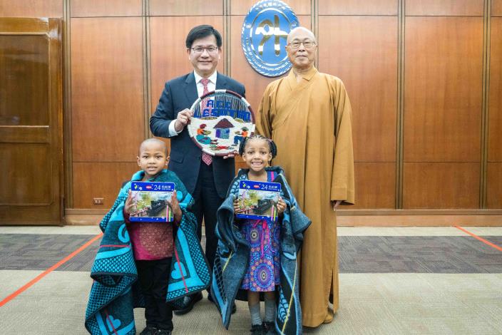 圖說三：阿彌陀佛關懷中心發起人慧禮法師（右後）及該中心院童代表致贈賴索托紀念品予外交部長林佳龍（左後）。