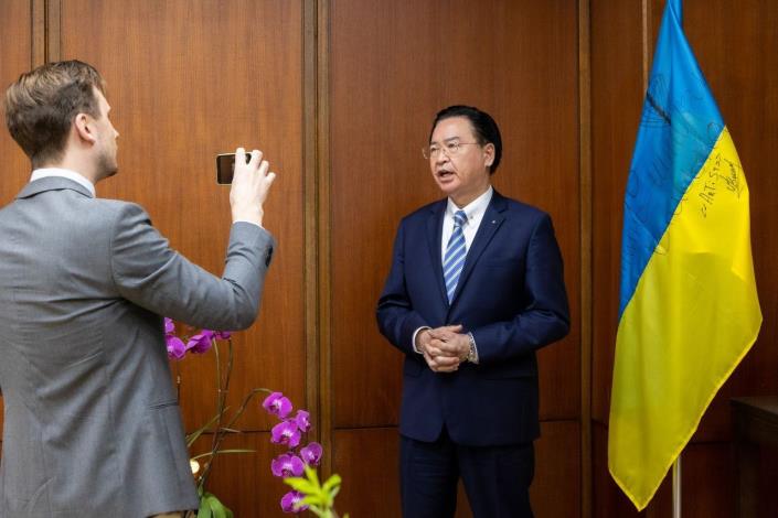 圖說二：外交部長吳釗燮向D社長說明陳列在會客室由烏克蘭前線戰士簽名的烏國國旗。